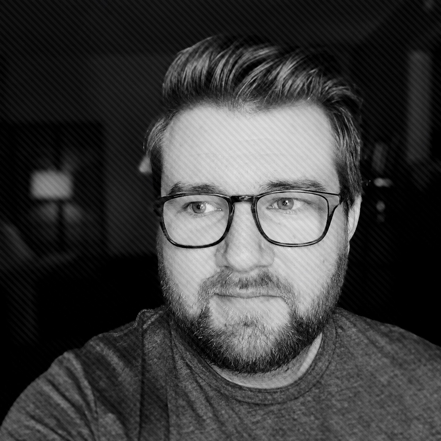 A black and white photo of Dave, a white man with blonde hair, a medium length beard and glasses.